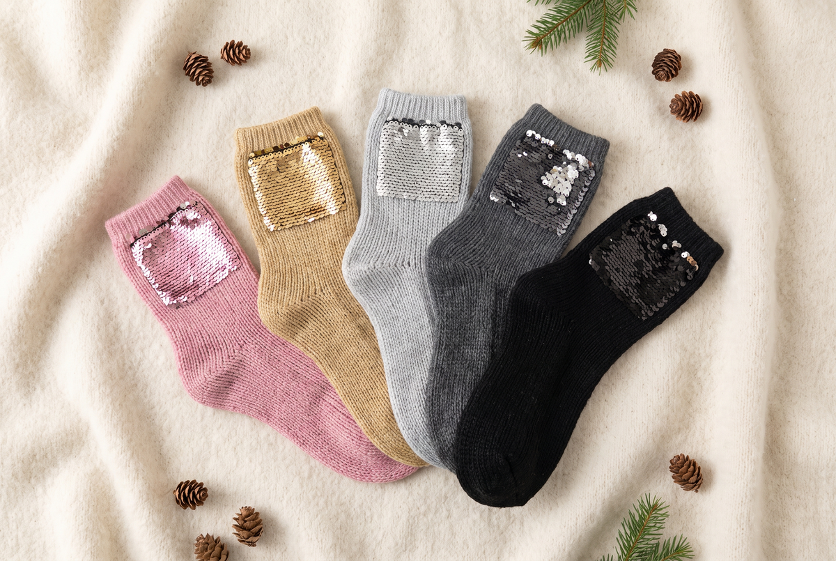 Plusieurs paires de chaussettes à paillettes de couleurs différentes disposées en éventail sur une couverture en laine Image